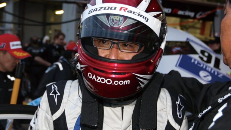 Akio Toyoda, chairman de Toyota, con el casco de piloto junto a un automóvil de competición.
