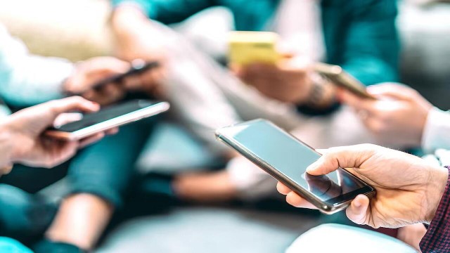 Personas realizando un pago acercando sus teléfonos celulares, ilustrando el uso de la tecnología NFC.