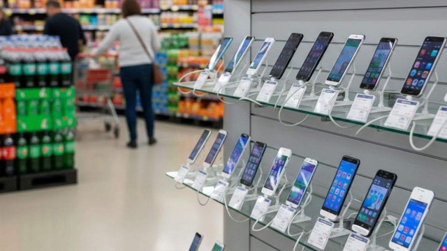 Persona sosteniendo un celular moderno con pantalla encendida, fondo neutro