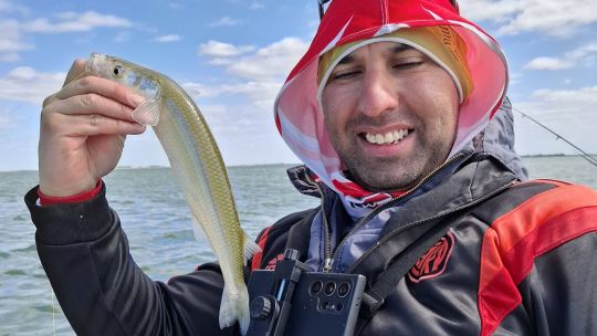 Persona pescando en un río o lago argentino en un día despejado