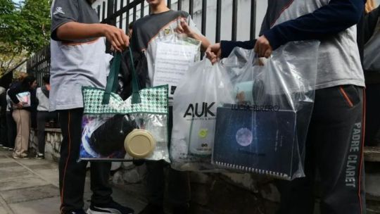 Estudiantes ingresando a una escuela con bolsas transparentes en lugar de mochilas.
