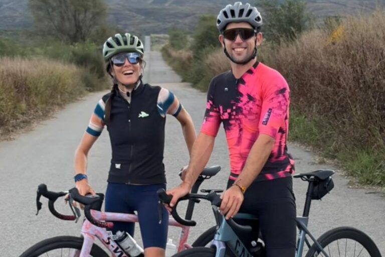 Juana Viale y Yago Lange en bicicleta, equipados para ciclismo, con paisajes serranos de San Luis de fondo.