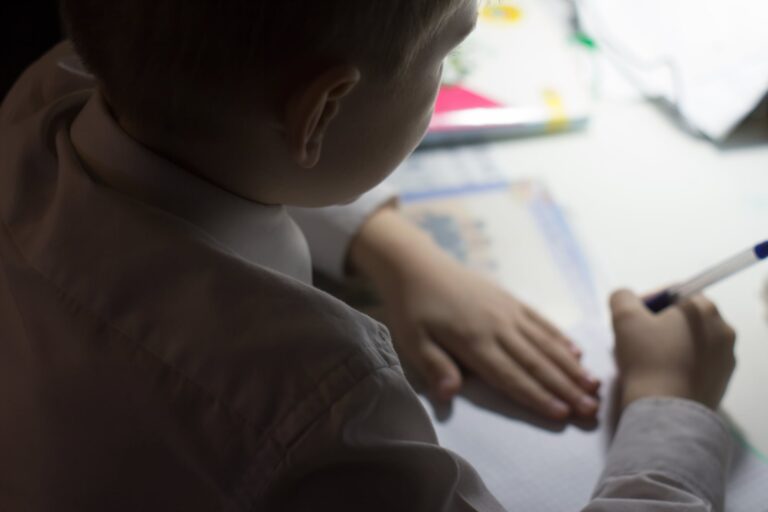 Niño escribiendo en un cuaderno en un aula escolar