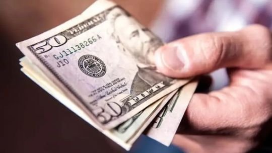 Billetes de dólar y monedas argentinas sobre una mesa