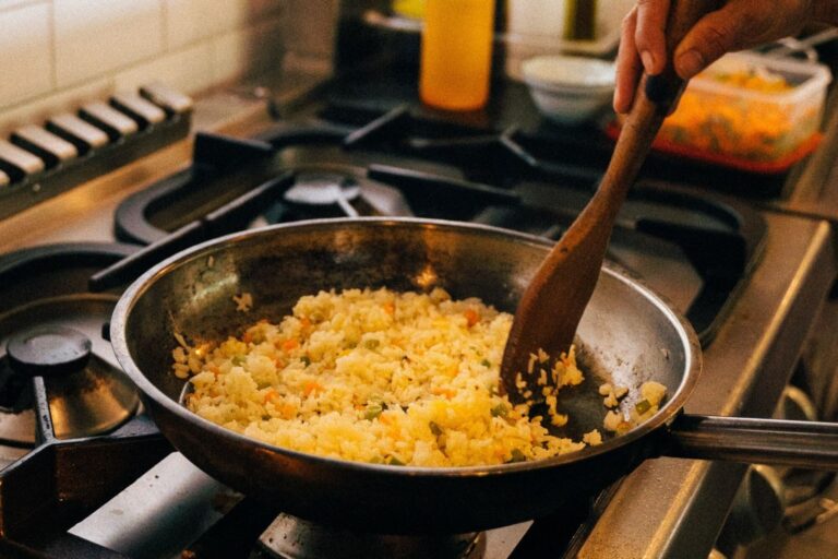 Arroz blanco cocido en olla con caldo y hojas de laurel
