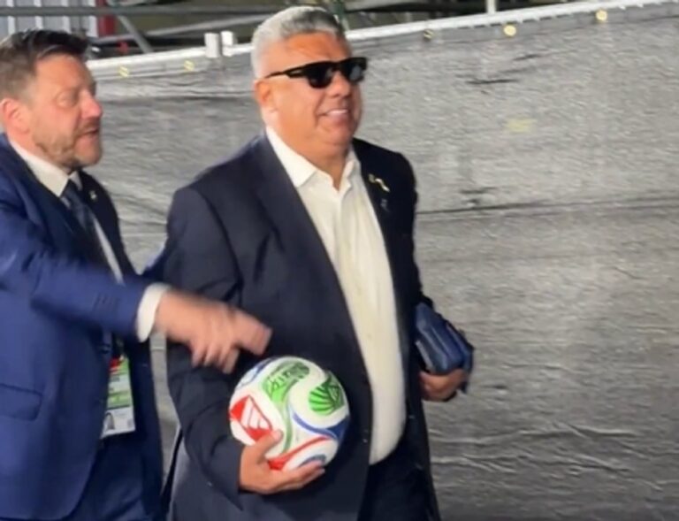 Claudio Chiqui Tapia con pelota y lentes negros saliendo del estadio