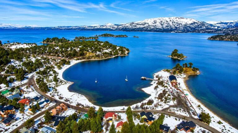 Vista de Villa Pehuenia con montañas nevadas y lago de aguas cristalinas